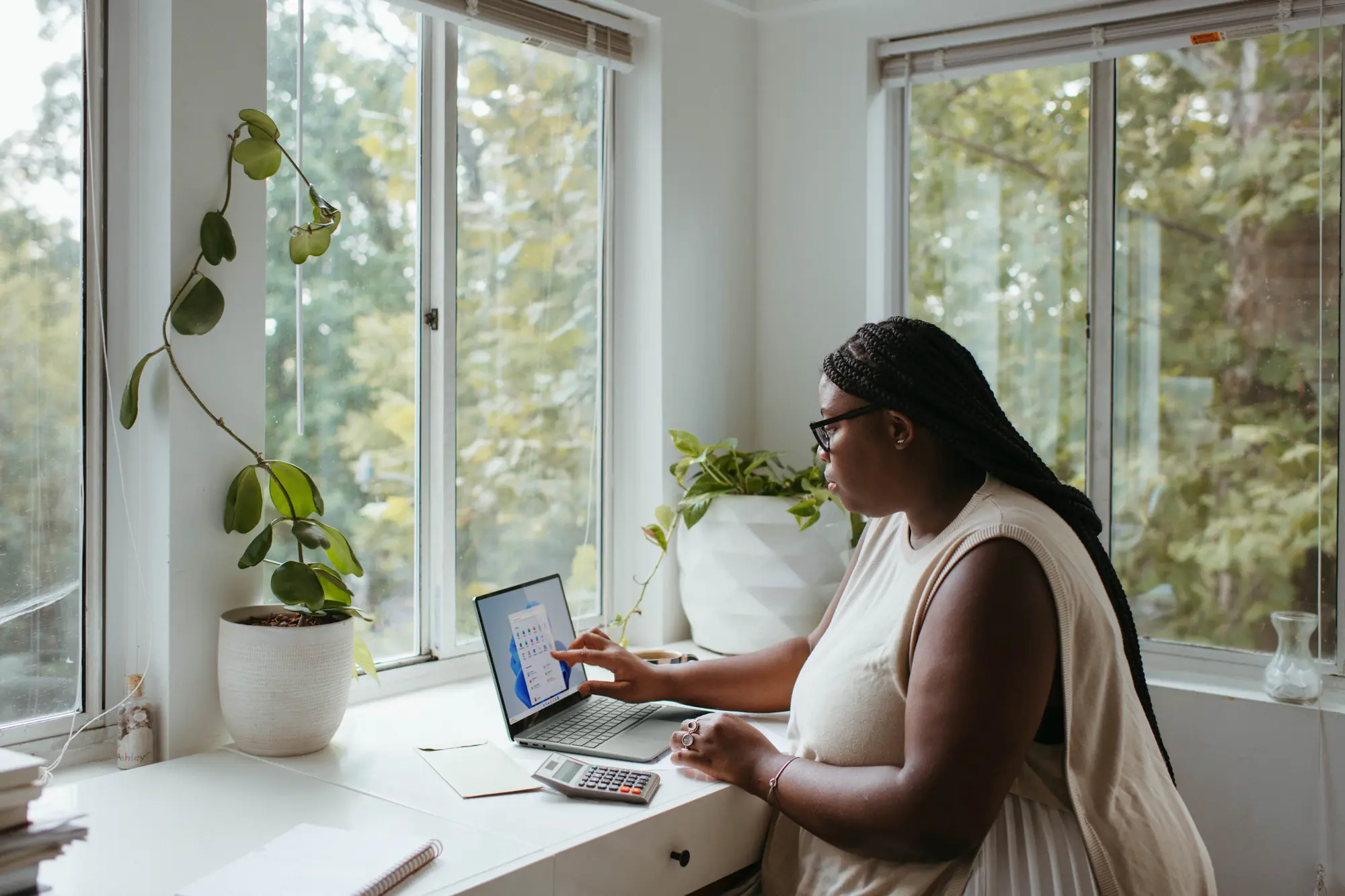 A woman sitting on a table in a clean environment, focused on her work as she searches to find house cleaning services that will do an amazing job on a deep clean and office cleaning
