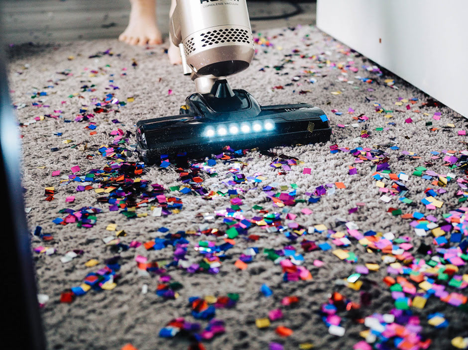 A person is cleaning the mess after a party with a vacuum